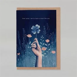 A whimsical Mother's Day card featuring a hand reaching up to touch a delicate blue flower against a dark background with other floral elements.