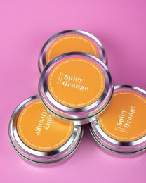 Spicy orange scented soy candles in round metal containers.