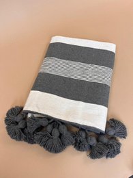Striped plaid wall mirror with horizontal stripes, pom-pom tassels, gray beige cream colors, modern geometric design.