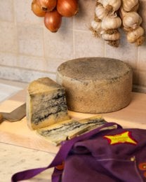 Pecorino cheese marbled with truffles, artisanal, creamy interior, round wheel form, earthy brown color.