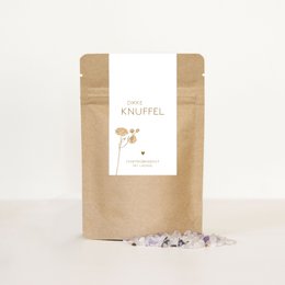 A large, cozy bath salt package in a natural kraft paper bag. The package features a simple, minimalist design with a small label. The bath salts appear to be a light, earthy color, suggesting a natural, soothing product.