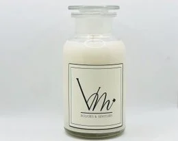 A tall, round white candle in a glass jar with a black and white label that says "Vhr". The candle appears to be a scented candle, likely made of wax. The product is part of a collection of scented candles with various fragrance names like "Sapin Magique", "Joie de Noël", and "Douceur Coton".