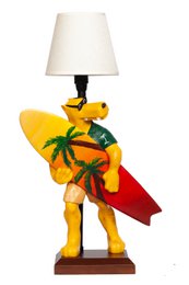  A wooden figurine of a surfer holding a surfboard, with a tropical palm tree design. The lamp has a white shade.