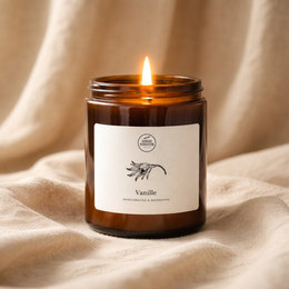 Tall, round vanilla-scented candle in a glass jar with a black label featuring a simple illustration.