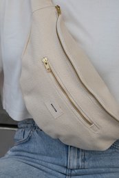  Beige shoulder bag with gold-tone zipper details and a minimalist design.