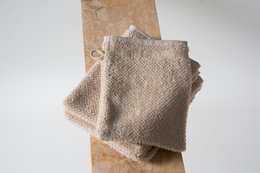 Soft, organic cotton washcloth in oak beige, woodland gray, and baby cream white colors. Rectangular shape with textured surface.