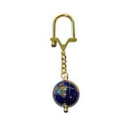  Lapis lazuli key ring with a globe-shaped charm in blue and gold tones. Made of metal with a keychain attachment.