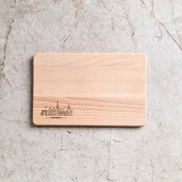  Rectangular wooden cutting board with a skyline design, made of light-colored wood.