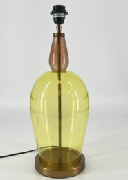 A tall, round glass lamp base in a vibrant yellow color with a brass-colored metal base and a black lamp shade. The lamp has a simple, modern design that would complement a variety of decor styles.