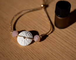 Aromatherapy bracelet with sea urchin-inspired design, featuring a round pendant with a carved pattern and natural stones in various pastel colors.