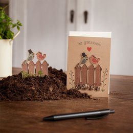 Congratulations card with bird motif, featuring a nature-inspired design with soil and plants.
