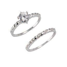 A set of white gold rings featuring a round diamond solitaire and a twisted band with additional diamonds.