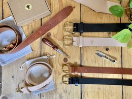 Handmade leather belt in brown, black, and natural colors, available in widths of 25mm and 40mm, and sizes ranging from XS to XL.