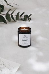 Eucalyptus-scented candle in a black glass jar with a wooden lid. Available in 120ml, 180ml, and 500ml sizes. Features a natural, earthy aroma.