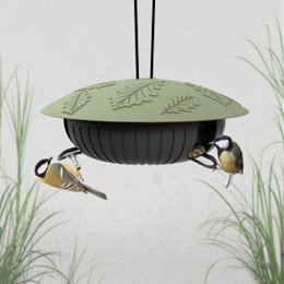  A green metal bird feeder with a leaf-shaped design, hanging from a metal rod. The feeder has multiple perches for birds to feed from, and a small bird is visible near the feeder.