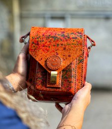  Handmade genuine leather crossbody bag in a vibrant orange and red floral pattern. The bag features a flap closure with a metal clasp and adjustable shoulder strap. The leather material gives the bag a high-quality, durable construction.