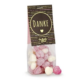 Assorted heart-shaped bonbons in a "Danke" (Thank you) gift bag. The bonbons come in various pastel colors, including pink, white, and purple. The bag has a simple, rustic design with stripes and a heart icon.