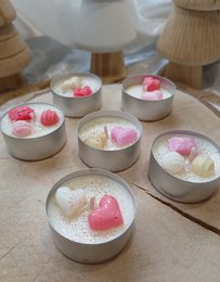  A white, ceramic Santa Claus candle with a jolly, round shape and a long, white beard. The candle is surrounded by small, decorative Christmas trees, creating a festive holiday scene.