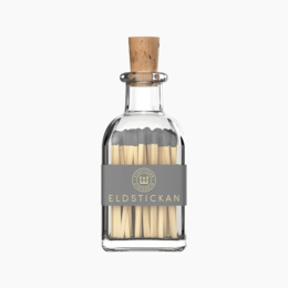 Small glass bottle with wooden cork lid, containing matches. The bottle has a simple, minimalist design.