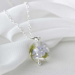 Silver necklace with a glass pendant featuring purple flowers and green leaves.