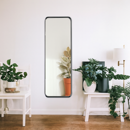  Oval steel-framed wall mirror, 30x120 cm, with natural plant decor.