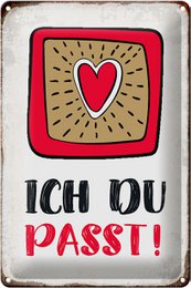 Decorative tin sign with a heart-shaped design and the text "Ich du passt!" (German for "You fit!"). The sign features a red heart icon surrounded by a retro-style frame and text.