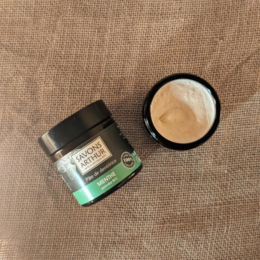 Organic peppermint paste toothpaste in a glass jar with a black lid. The toothpaste is green in color and has a natural, minty scent.