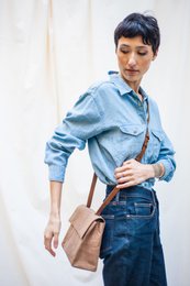 Camel-colored leather handbag with adjustable strap and flap closure.