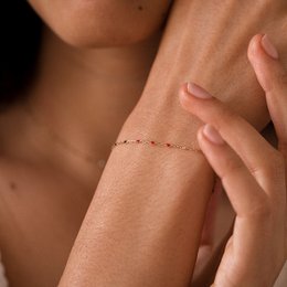 Thin, delicate bracelet with a minimalist design featuring a chain of small beads or stones in various colors.