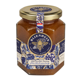 Dutch heather honey in a glass jar with a blue and white label. The honey has a rich, golden color and a smooth, creamy texture.