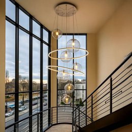 Elegant modern pendant light with multiple glass globes in various colors including gold, black, and clear. Features a sleek, minimalist design with a circular frame and adjustable hanging rods.