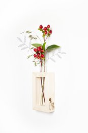 Tall, round glass vase with red berries and green leaves.