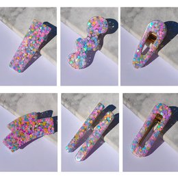 Colorful resin hair clips in a heart shape, featuring a variety of vibrant floral and confetti-like patterns. Suitable for kids' hair accessories.