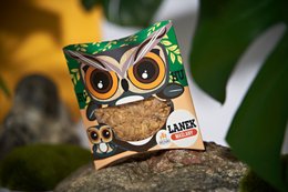 A round, golden-brown cookie with a whimsical owl-themed packaging design. The packaging features a large, cartoon-style owl face with big, expressive eyes and a playful expression.