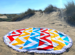 Colorful round beach towel with abstract geometric pattern, suitable for beach or picnic use.