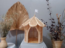 Whimsical, tent-shaped kids play structure made of woven rattan with a peaked roof and decorative details. Suitable for indoor or outdoor use.