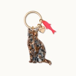 Keychain featuring a cat design with a red tassel accent. Made of durable materials suitable for kids.