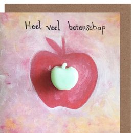 A colorful handmade card with a large red heart shape and a small green apple-shaped object inside it. The text on the card reads "Heel veel beterschap" which means "Get well soon" in Dutch.