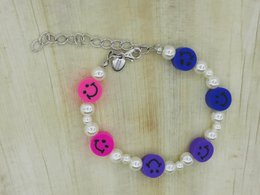 A colorful kids bracelet with pink and purple buttons, white beads, and a metal chain.