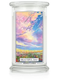Large round scented candle with a floral and fruity fragrance, featuring a colorful sunset landscape design.
