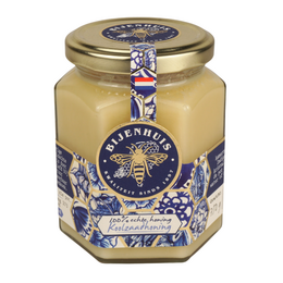 Dutch rapeseed honey in a glass jar with a blue and white floral label. The honey is a pale yellow color and has a smooth, creamy texture.