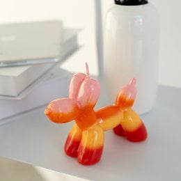 Tall, round, orange and pink balloon dog-shaped candle.