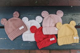  Cozy knit beanies in a variety of colors including pink, red, beige, yellow, and brown. Featuring a classic pom-pom design for a stylish and warm winter accessory.