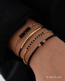 A set of three elegant bracelets in gold, rose gold, and light silver tones, featuring a chic black and metallic design. The bracelets are made of beads and have a stylish, minimalist appearance.
