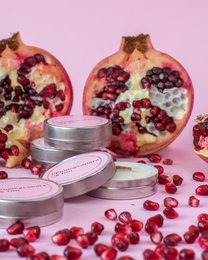 Pomegranate scented soy candles in round, tall shape with pomegranate seeds visible.