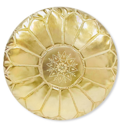 A round, gold-colored pouf with a textured, faux leather cover. The pouf has a decorative, sunburst-like pattern on the surface.