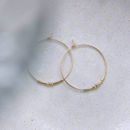 Gold-tone hoop earrings with a simple, minimalist design. The hoops have a smooth, circular shape and a sleek, polished finish.