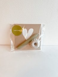 Beige gift box with white heart design, containing a white candle and a wooden stick. Suitable for gift tags or decorative purposes.