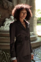  A grey wool blazer with a belt and exposed light blue lining on the sleeves, designed for women.