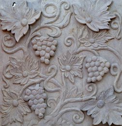 Decorative wall panel featuring carved grape clusters, leaves, and floral motifs in natural and gray finishes.